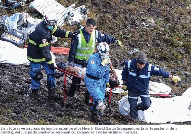 En la foto se ve un grupo de bomberos, entre ellos Hernán David García (el segundo en la parte posterior de la camilla),  del cuerpo de bomberos aeronáutico, sacando una de las víctimas mortales.